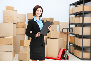 Young woman with clipboard in logistics company warehouse