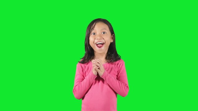 Cute little girl standing in the studio looks shocked and surprised, shot with green background