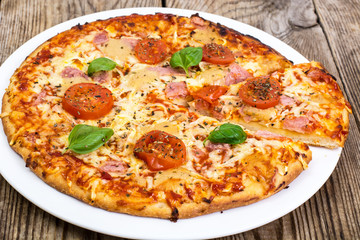 Pizza with ham, cheese, tomatoes and basil
