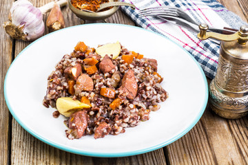 Pilaf with red rice with chunks of beef, carrots and garlic