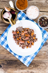 Pilaf with red rice with chunks of beef, carrots and garlic