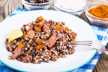 Pilaf with red rice with chunks of beef, carrots and garlic