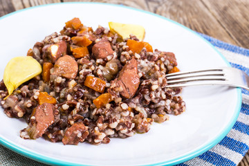 Pilaf with red rice with chunks of beef, carrots and garlic