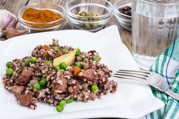 Boiled red rice with vegetables and slices of chicken on a woode