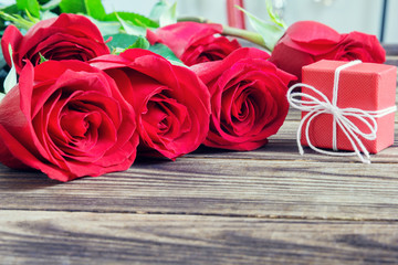 gift and red roses on a wooden background