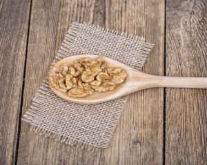 Walnuts on wooden spoon. Wooden rustic brown background.