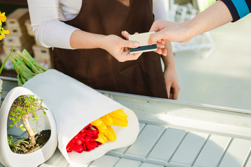 buyer's hand giving payment card for payment flowers to saleswoman. Cashless payments