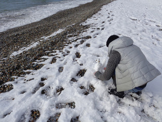 Teen making snowman on winter beach