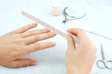Obraz na płótnie Canvas Woman making manicure using nailfile with nail care tools backg