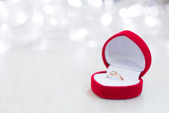 close-up of an open red box with a wedding ring on a light wooden background, flashing lights
