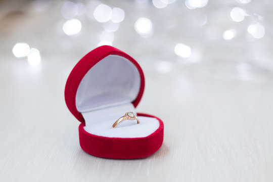 close-up of an open red box with a wedding ring on a light wooden background, flashing lights