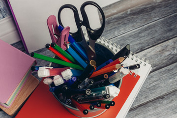 pencils pens and scissors on a red notepad, stickers on a wooden background