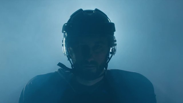 CINEMAGRAPH - seamless loop. CU Portrait of Caucasian male ice hockey player in black uniform, looking into the camera. 4K UHD