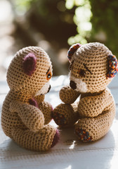 Two teddy bears on a wooden table looking at each other