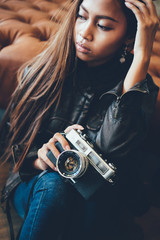 Cool hipster girl in a leather jacket holding camera
