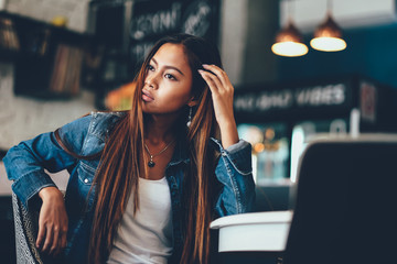 Gorgeous young woman in blue jeans sittingon the chair