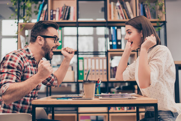 Yes! happy business partners triumphing with raised fists