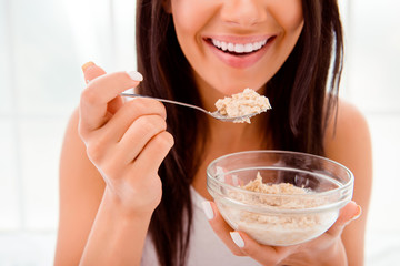 Close up of happy cheerful woman eating porridge in morning