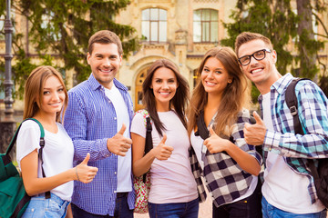 Successful happy best friends standing near campus and gesturing