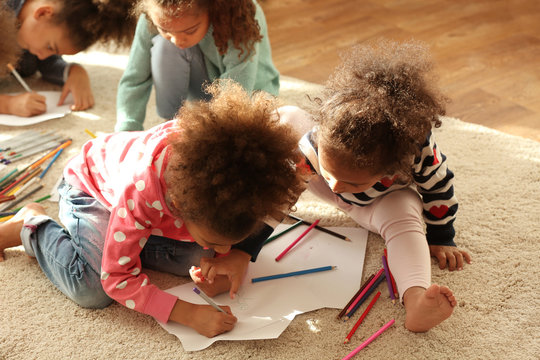 Four African girls sitting on floor and painting