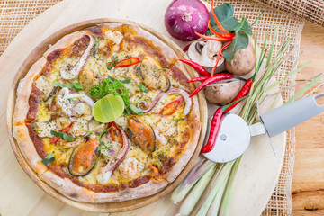 Delicious Seafood Pizza on a wooden table with ingredients aroun