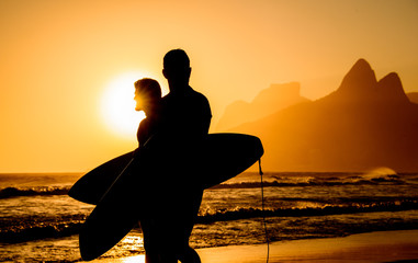 Golden sunset in Ipanema Beach with Two Brothers, Dois Irmaos Mountain and two surfers silhouettes,...