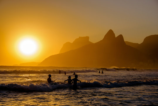Unidentifiable silhouettes enjoying late afternoon sun rays on Ipanema beach in Rio de Janeiro, Brazil. Ipanema is one of the most expensive places to live in Rio.