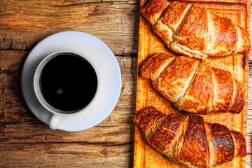 Coffee and croissant on wooden background