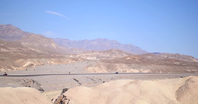 Cars Driving Through Barren Desert Landscape - Death Valley National Park, California