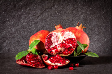 Fresh red pomegranate and seed  with leaves over black stone 