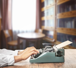 Man working on retro typewriter at desk in library