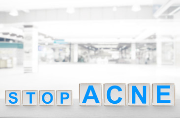 Text STOP ACNE of wooden cubes on table against blurred hospital background. Skin care concept