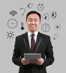 Business and time management concept. Young man with tablet on gray background