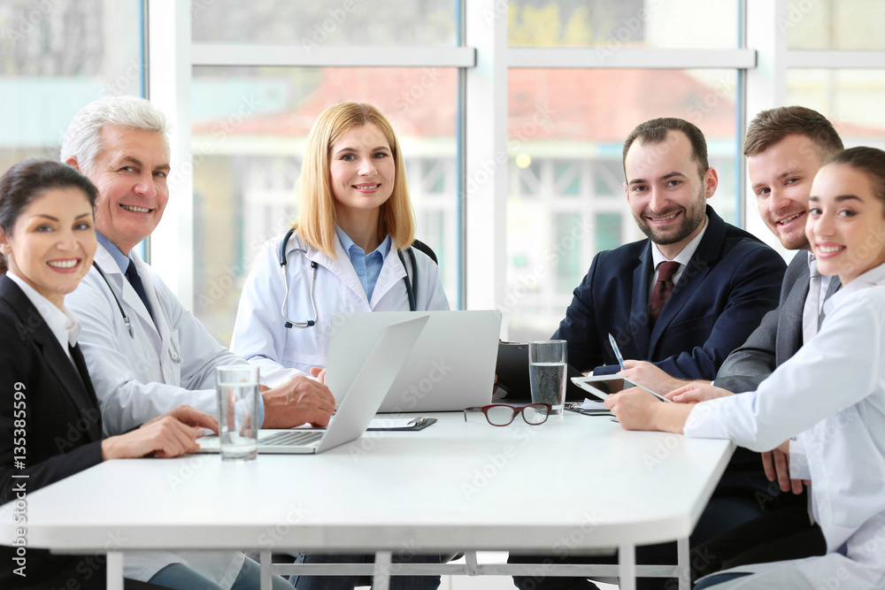 Wall mural Team of doctors sitting at table in clinic