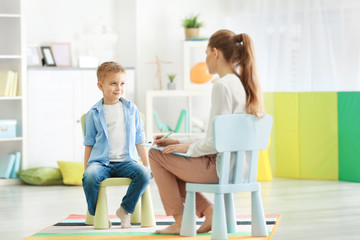Young female psychologist working with little boy in office