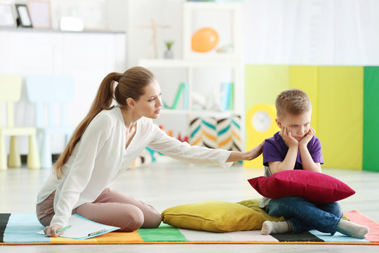 Young female psychologist working with little boy in office
