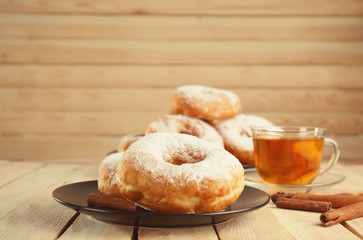 Plate with delicious doughnuts and cup of tea on table