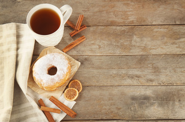 Delicious homemade doughnut with sugar powder and cup of tea on wooden table