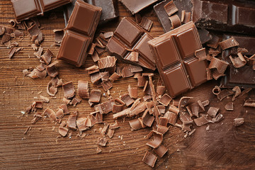 Broken chocolate pieces and shavings on wooden background