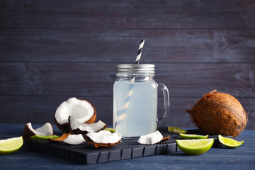 Fresh nuts and mason jar with coconut water on wooden background