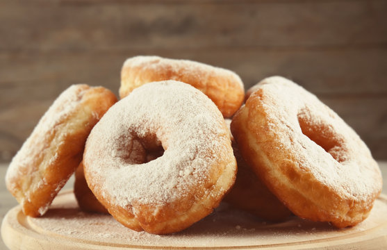 Delicious homemade doughnuts with sugar powder on wooden board