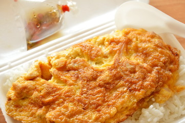 fried egg on rice in foam box with plastic spoon ready for eat