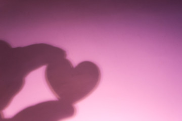 valentines'day, shadow heart in hand on gradient pink background with blurred effect.