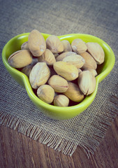 Vintage photo, Pistachio nuts in bowl on wooden table, healthy eating