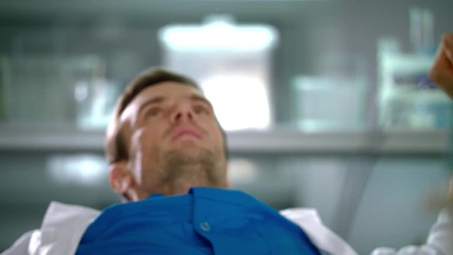Doctor stretching at laboratory. Laboratory worker yawning at lab. Man warming up. Scientist in lab. Tired doctor in lab. Portrait of yawning man in white coat. Doctor yawning at work