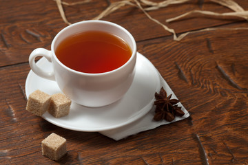 Cup of brewed tea and brown sugar on wooden table