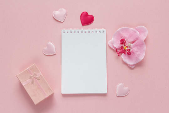 Open blank notebook with gift box, orchid flower and hearts on a