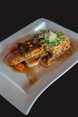 Pasta with chicken fillete on white plate isolated in black