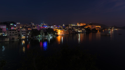 Glowing cityscape at Udaipur by night. The majestic city palace reflecting lights on Lake Pichola, travel destination in Rajasthan, India