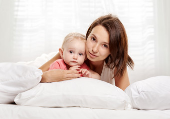 Happy family mother and baby having fun on bed